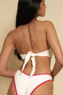 Cream bandeau bikini top with tie-back closure and raspberry pink binding detail on matching bottoms.