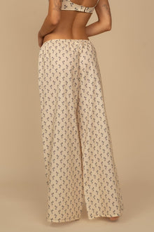 Cream wide-leg pants with small black floral print and drawstring waist.