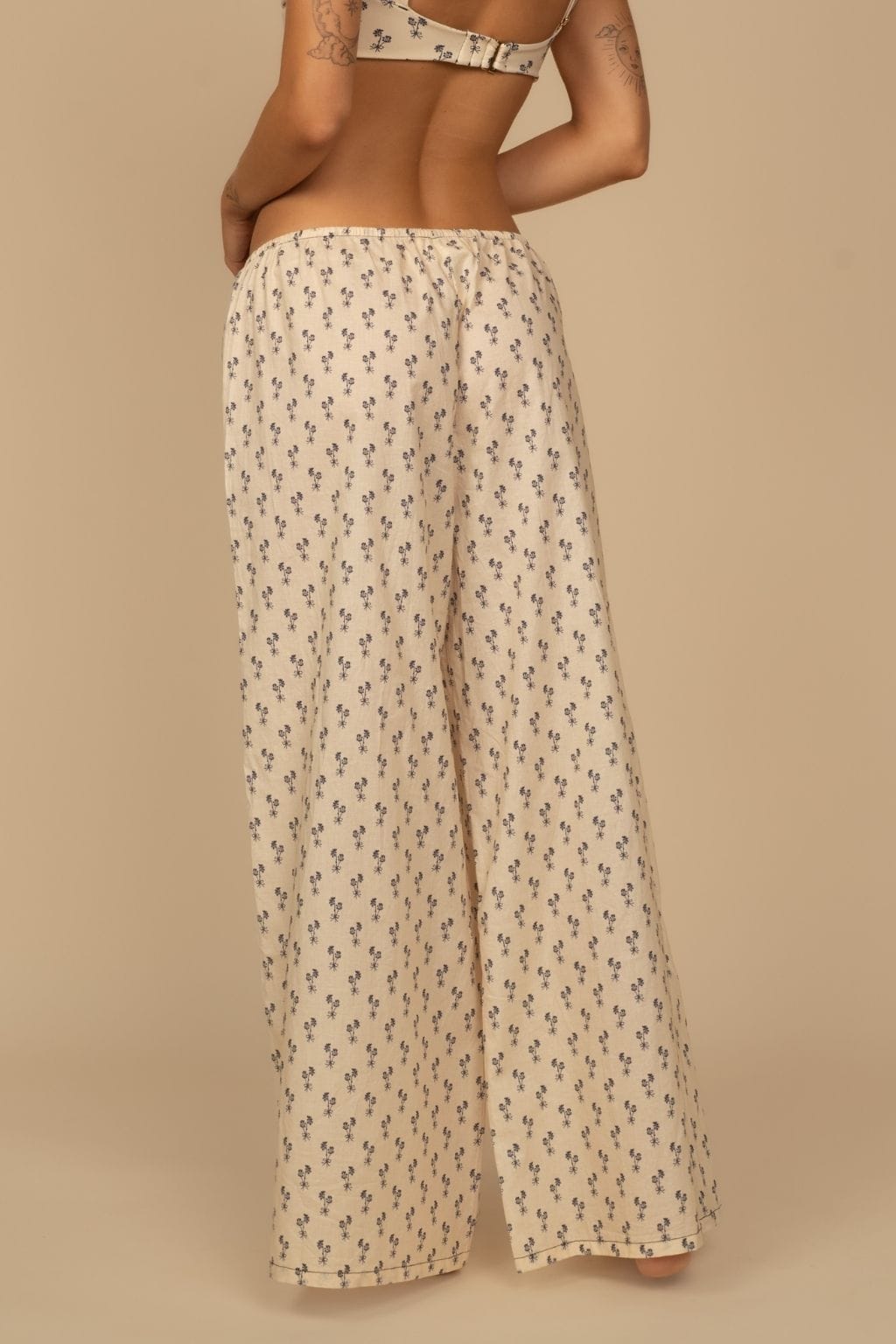 Cream wide-leg pants with small black floral print and drawstring waist.
