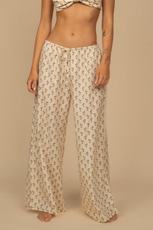 Cream wide-leg pants with small floral print and drawstring waist.
