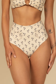 Cream bikini bottom with small black floral print and curved pocket details on front.
