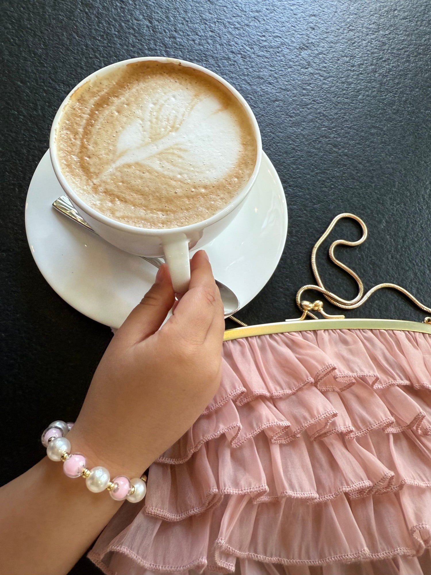 Child wearing pink ballerina pearl necklace and bracelet set, elegant ballet inspired jewelry for girls, paired with dusty pink ruffled handbag