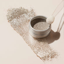 An open jar of Manucurist Glitters Duo Silver  Mirror with pearlescent shine is spilled across a light surface; a sponge tip applicator rests on the edge of the jar.