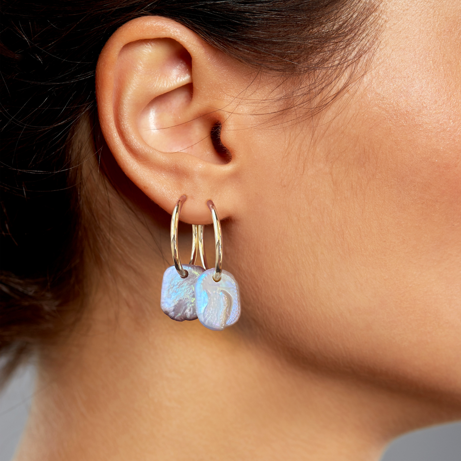 14k gold White Rectangular Coin Pearl Hoops styled on a ear together 