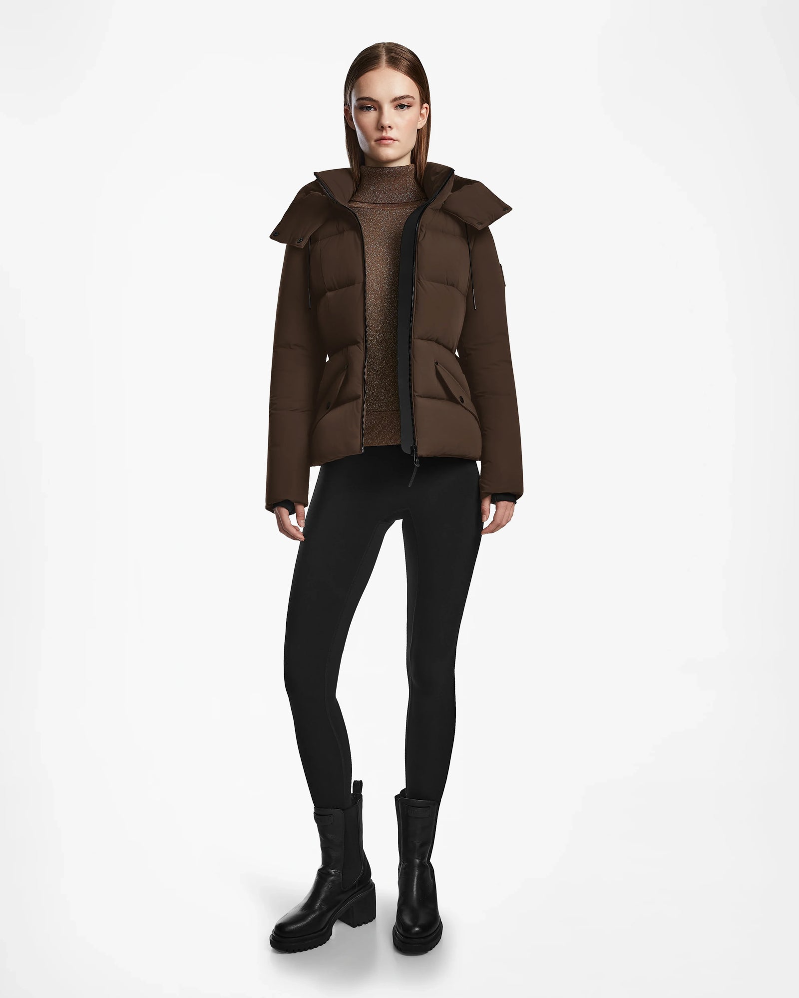 A woman faces forward wearing the Rudsak ADELINE - 8124544 Mocha quilted short down puffer over a brown turtleneck, black leggings, and black ankle boots against a plain white background.