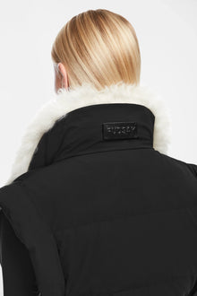 A person with straight blonde hair, seen from behind, wears the Rudsak AIDIA - 8124730 Black cropped jacket with a luxe white shearling collar. A black rectangular label is on the collar. The background is plain white.