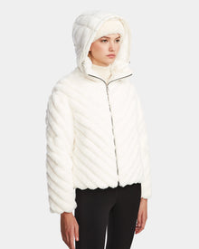 Someone wearing the Rudsak ANASTASIA - 8124804 Iceland white, hooded, RDS-certified down quilted jacket with diagonal stitching and black pants stands against a plain light gray background.