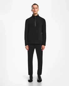 A man faces forward against a white background, wearing the Rudsak BECK - 6524538 Black men’s fleece pullover. He has black pants and shoes, with arms at his sides and a neutral expression.