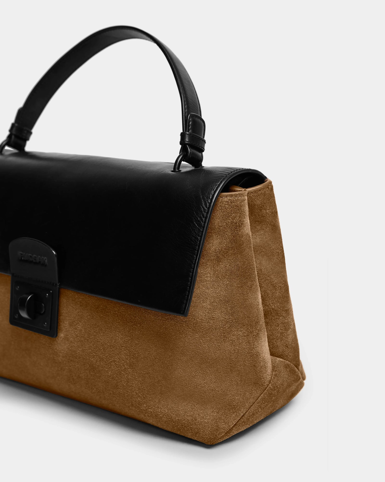 The Rudsak ESMA - 8324519 Camel handbag features a brown suede body, black leather flap, top handle, removable shoulder strap, and a rectangular black clasp. Shown against a plain light gray background.