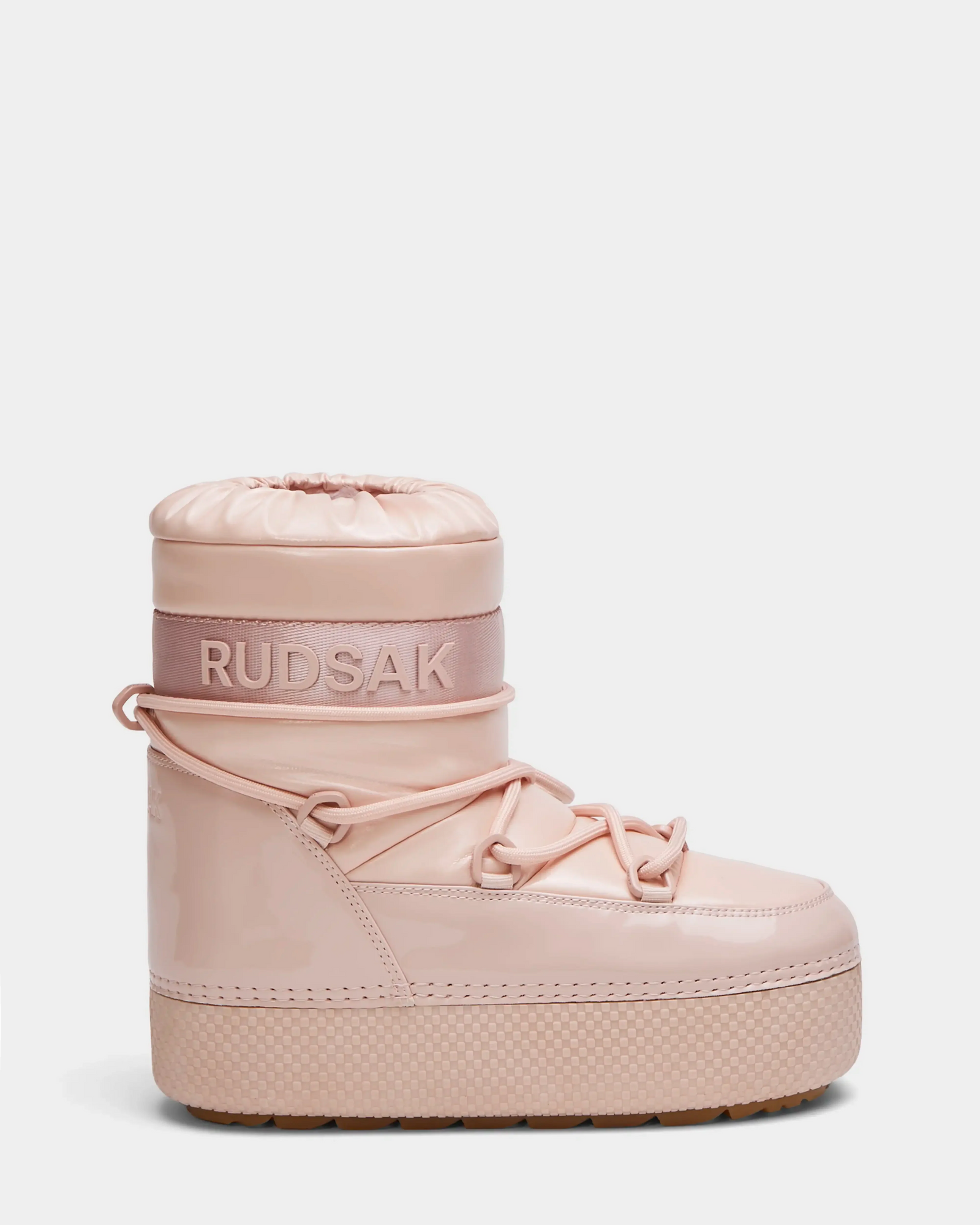The HARLOW Y - 1223500 Pastel Pink by Rudsak is a shiny, padded kid’s moon boot with a thick sole, lace-up detail, RUDSAK branding on the ankle band, and a drawstring top—perfect for winter adventures.