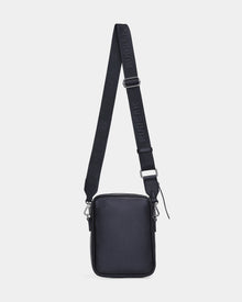 The Rudsak HUBERT - M324500 Black is a small, rectangular crossbody bag with a textured black surface, silver hardware, and an adjustable strap with embossed RUDSAK branding, shown against a plain white background.