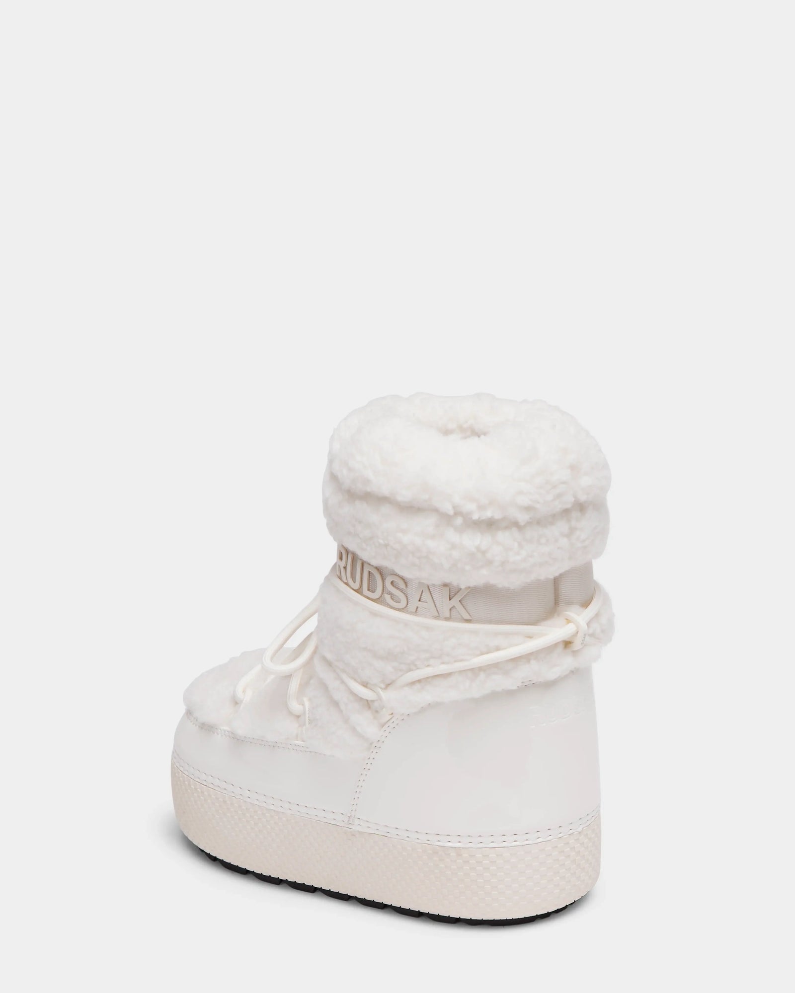 The KATHY Y - 1224500 Iceland by Rudsak is a white water-repellent winter boot featuring plush shearling texture, shiny trim, lace-up detail, and RUDSAK logo on the padded collar, finished with a thick textured sole. Shown against a white background.