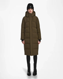 A person faces forward wearing the Rudsak MAO M - 8123598 Army women’s down puffer coat in olive green Stormshell, paired with a hood, black beanie, black leggings, and boots against a plain white background.