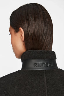 A person with straight, dark brown hair is seen from behind wearing Rudsaks MILANA - 8524604 Black textured coat with a leather collar embossed RUDSAK, layered over a chic teddy sweater for extra warmth and style.
