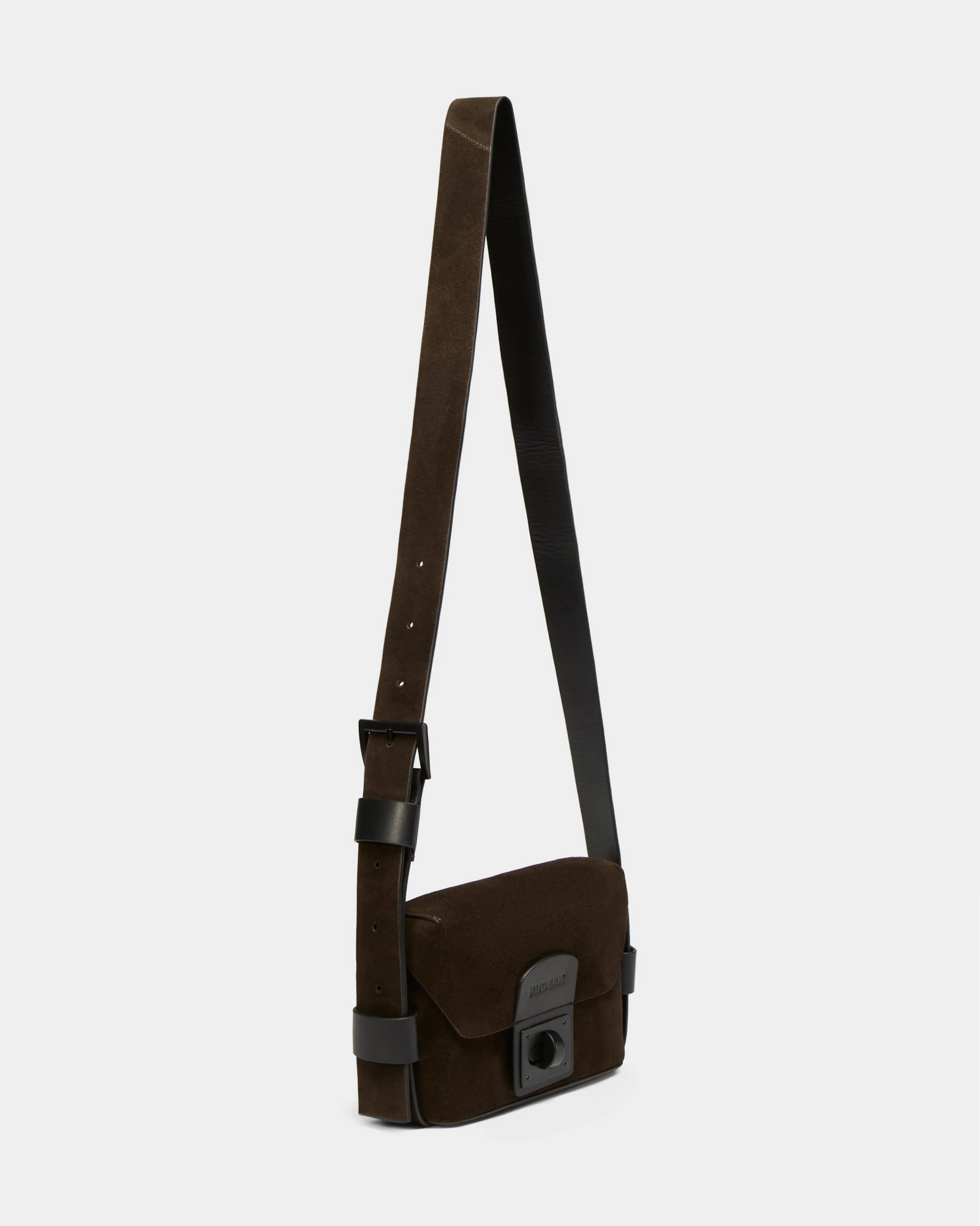 The Rudsak OFILIA S - 8324521 Espresso is a dark brown suede crossbody bag featuring a wide, adjustable leather strap and a front flap with a black buckle.