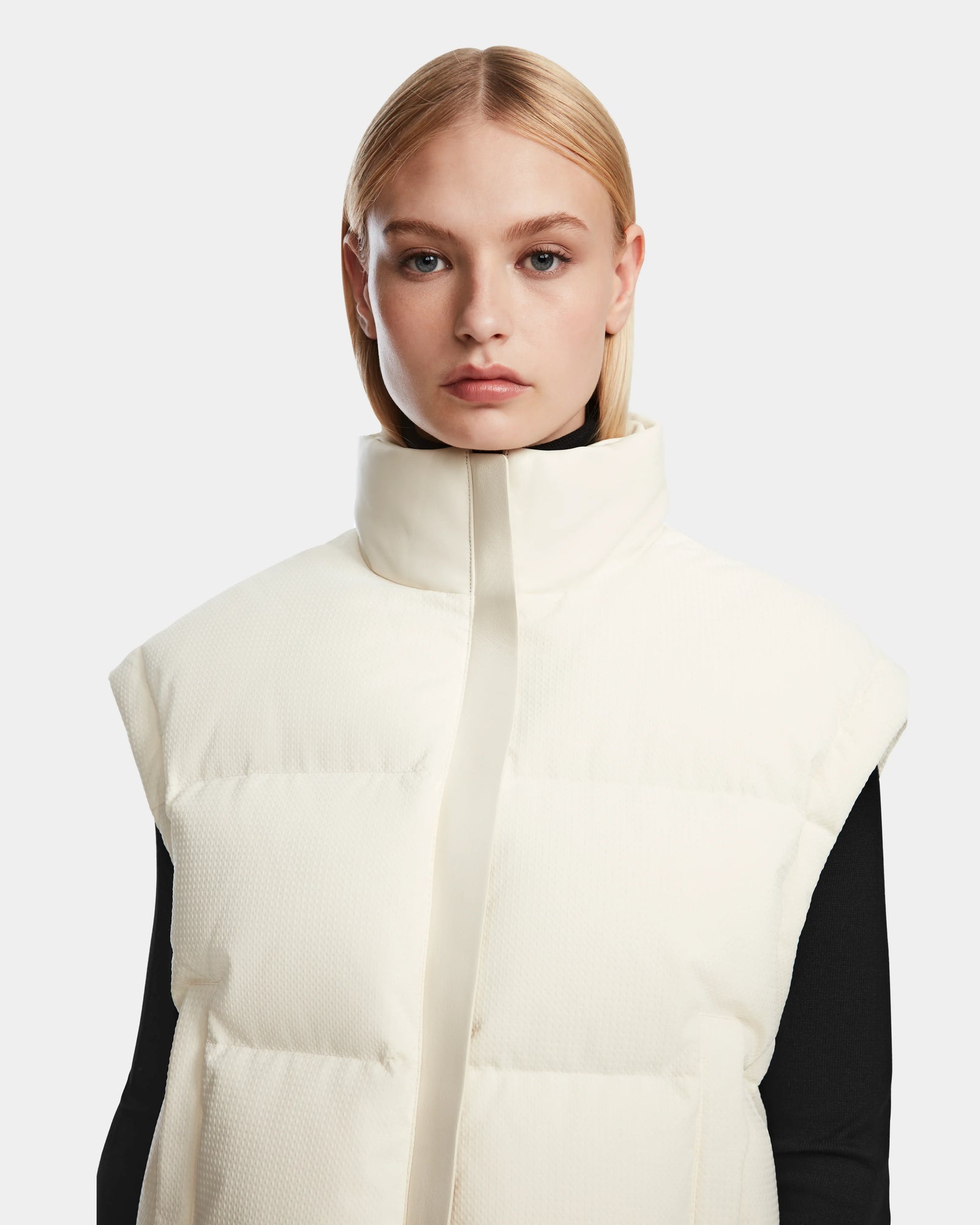 A woman in a white vest elevates her look with the Rudsak OPRAH - 8124708 Iceland women’s cropped down puffer, adding a modern touch to her outfit.