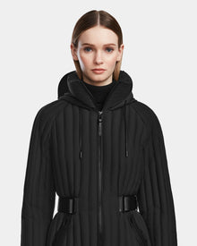 A woman wears the PETRAS - 8124725 Black womens light down jacket by Rudsak, elegantly styled with a vegan leather belt.