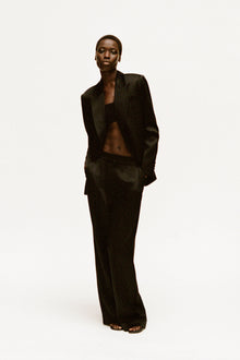 Black wide-leg pant with high waist and straight silhouette, styled with matching blazer.
