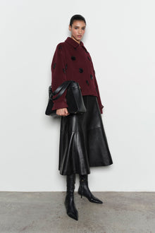 Burgundy wool jacket with black beaded embellishments and collar, worn with black leather midi skirt and boots.