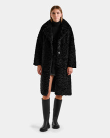 A woman exudes effortless elegance in the Rudsak ANNABELLE FSU - L125512 Black, a stylish women’s reversible trench coat that showcases timeless sophistication.