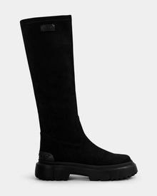 The Rudsak AVOLA - L225514 Black is a tall women’s knee-high boot in black faux suede with a chunky sole, smooth finish, rounded toe, and a rectangular label near the top—perfect for stylish city comfort.