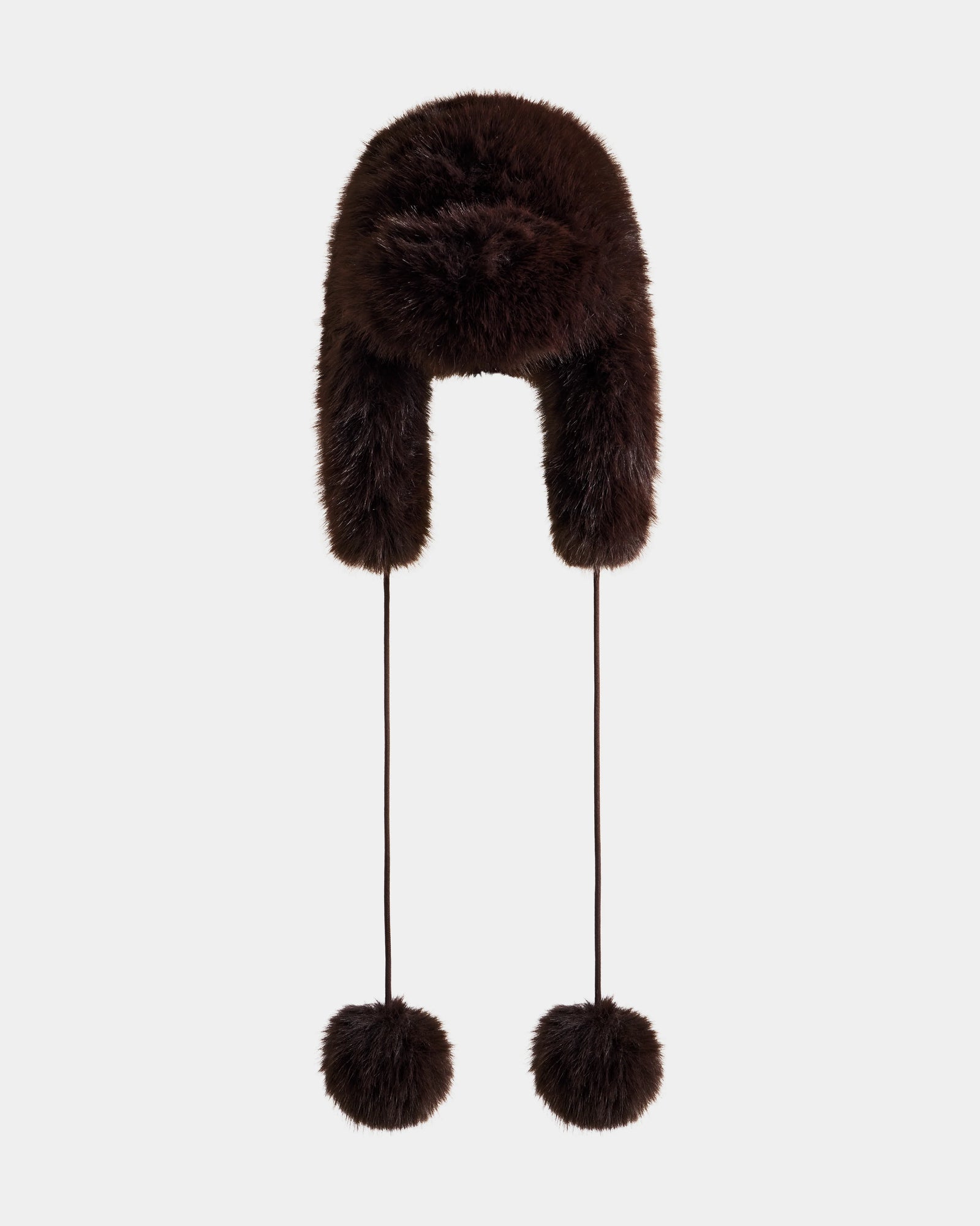 The Rudsak DEMI - L425539 Espresso is a dark brown women’s faux-fur aviator hat with ear flaps and two long strings topped with large fur pom-poms, shown against a plain light background.