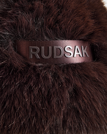 Close-up of the Rudsak DEMI - L425539 Espresso women's faux-fur aviator hat in dark brown, featuring a black ribbon with metallic RUDSAK letters, highlighting the stylish winter accessory’s luxurious texture.