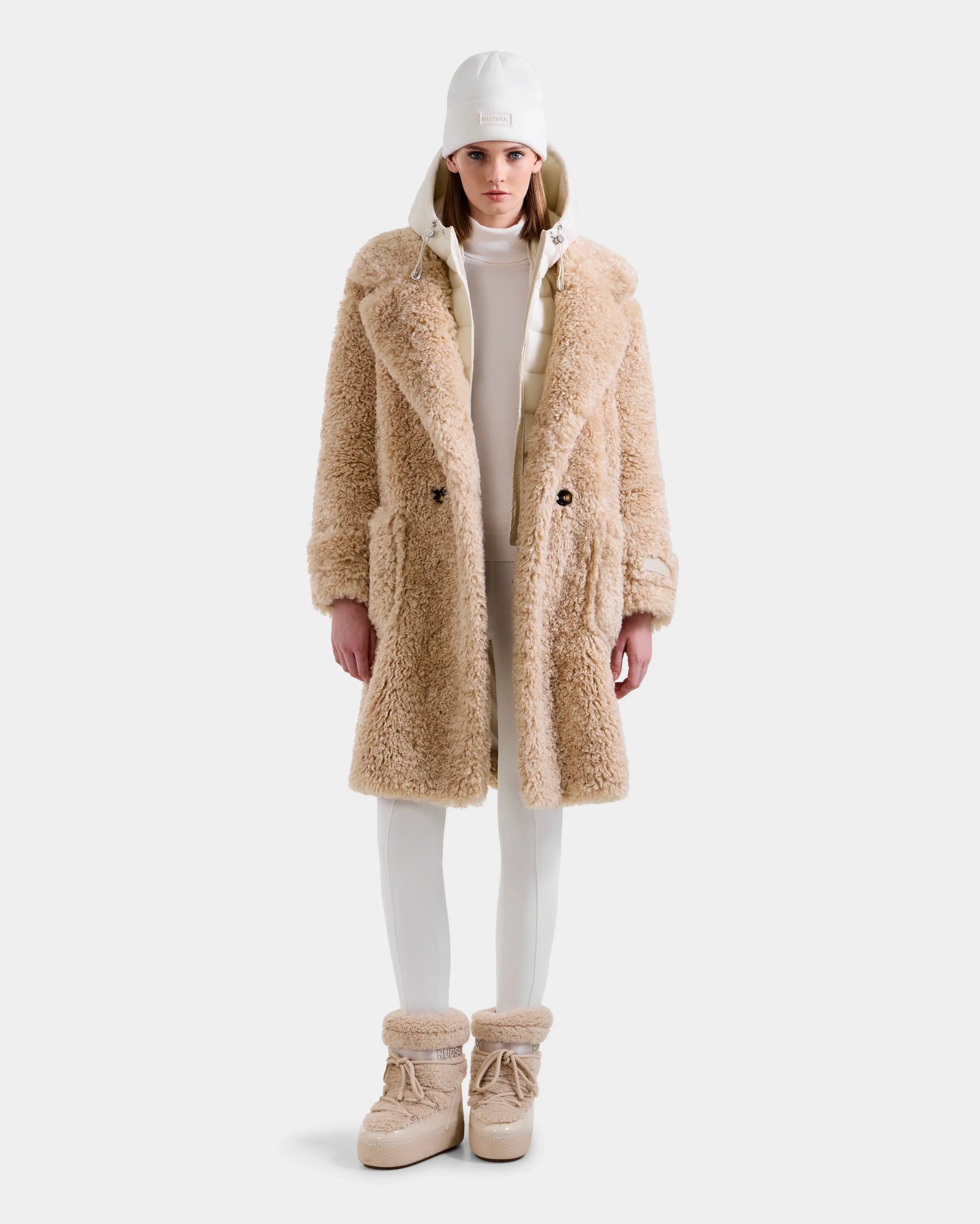 A person stands facing forward against a plain white background, wearing the Rudsak EMRYN - L125588 Vanilla teddy jacket for a cozy winter look.
