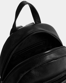 Close-up of the Rudsak KATTY - L325014 Black women’s mini backpack in black pebbled leather, with the main zipper partially open to show an interior pocket and textured lining.