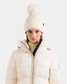 A woman faces forward against a plain light background, wearing the Rudsak LANYA - L423514 Iceland cream puffer jacket and a matching women's pom pom hat.