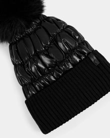 The Rudsak LANYA - L423514 Metallic Black is a shiny black puffer winter hat with a wool-blend ribbed knit cuff and a large black faux fur pom-pom, shown on a white background.