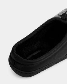 Close-up of the Rudsak MILTON - M225504 Black men’s quilted vegan leather slipper, featuring a textured sole, plush faux-shearling lining, rounded toe, and visible stitching, viewed from above and slightly to the side.