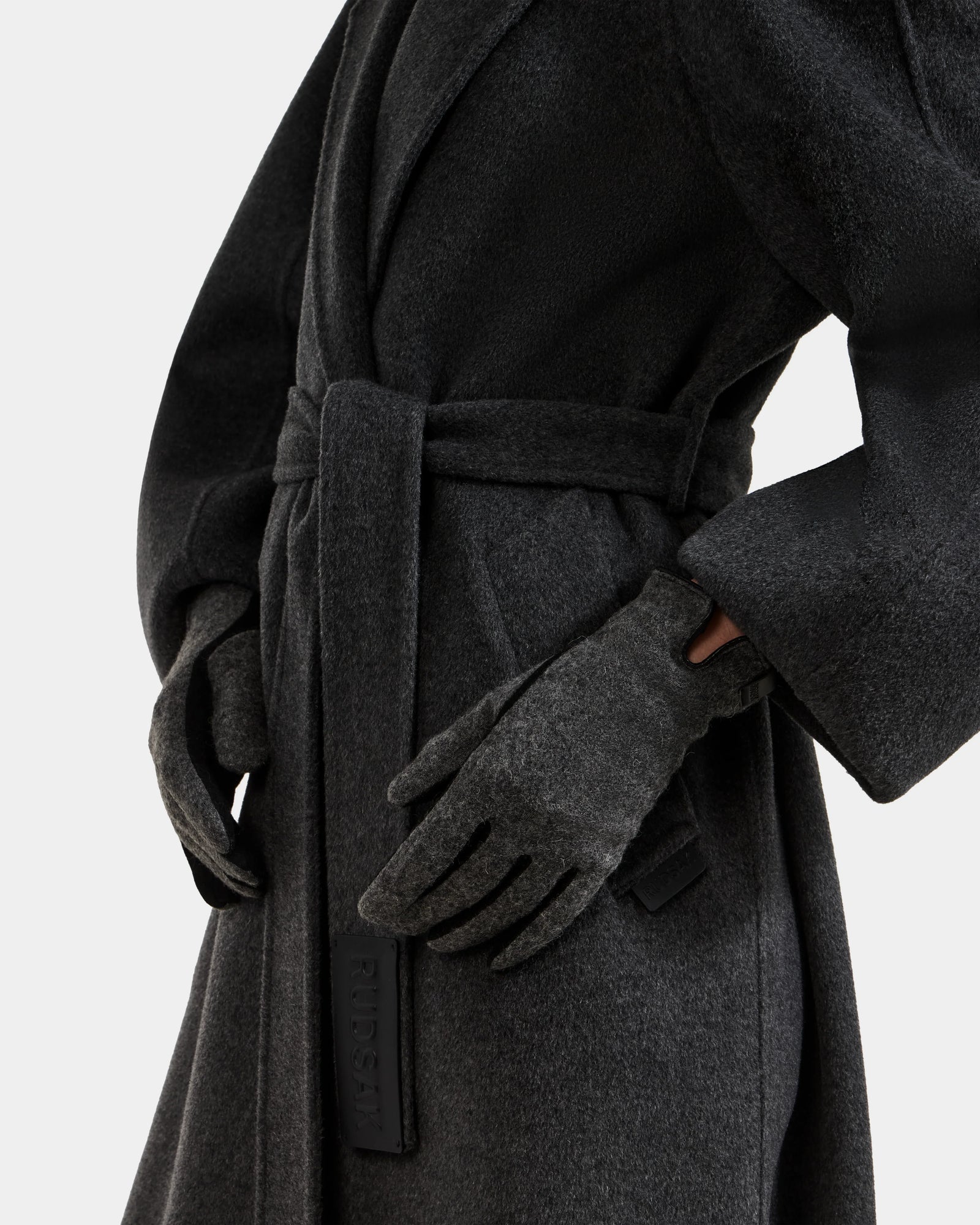 A person wears the OLGA - L425541 Grey coat by Rudsak with matching women’s wool gloves, standing against a plain background with one hand on their hip. Only their torso and arms are visible.