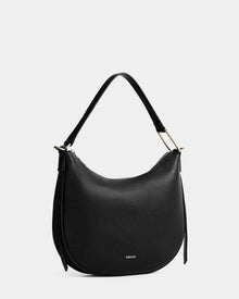 The Rudsak SYLVIA - L325515 Black is a black crescent leather handbag featuring a single short strap, gold-tone hardware, and subtle branding, displayed on a plain light gray background.