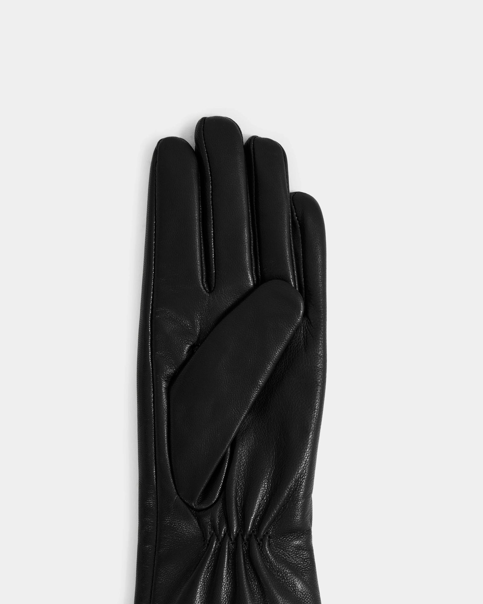 The Rudsak TORRI - L425544 Black women’s leather glove is shown palm-side up on a light gray background—a true winter essential.