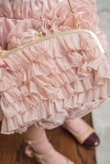 Close up of dusty pink organza ruffle handbag showcasing layered sheer ruffles, gold clasp closure, and delicate chain strap