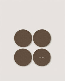 Four round, brown Merino wool coasters by Graf Lantz are arranged in a square on a white background. One features 