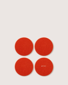 Four red circular felt coasters, crafted from luxurious German Merino wool by graf lantz, are set in a square on a white background. One coaster is elegantly printed with graf lantz in small white letters.