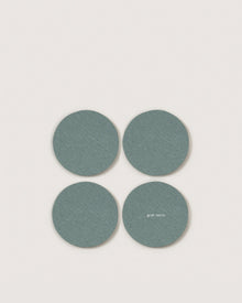Four round, teal Merino wool coasters by Graf Lantz are arranged in a square on a light background. One features the small white Graf Lantz logo, adding stylish, sustainable flair to your home decor.