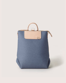 The Graf Lantz backpack, a chic and multifunctional piece, features a blue fabric body with light brown leather accents like a top handle and zipper. Positioned on a plain white background, it exemplifies commitment to sustainable fashion.