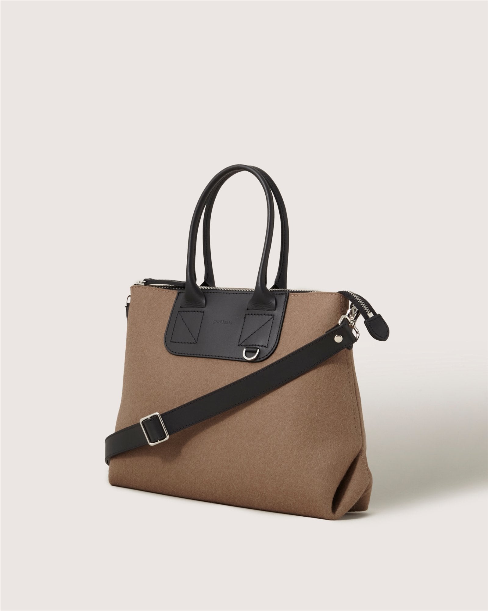 A brown Graf Lantz handbag with black leather handles, an adjustable shoulder strap, and a black leather patch near the top, set against a plain light background.