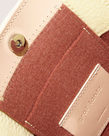 Close-up of the Graf Lantz Jaunt Midi Tote shows a magnetic snap closure, crafted from beige and brown Merino wool felt and leather with visible stitching. A text-printed leather label completes this stylish mid-size carryall.