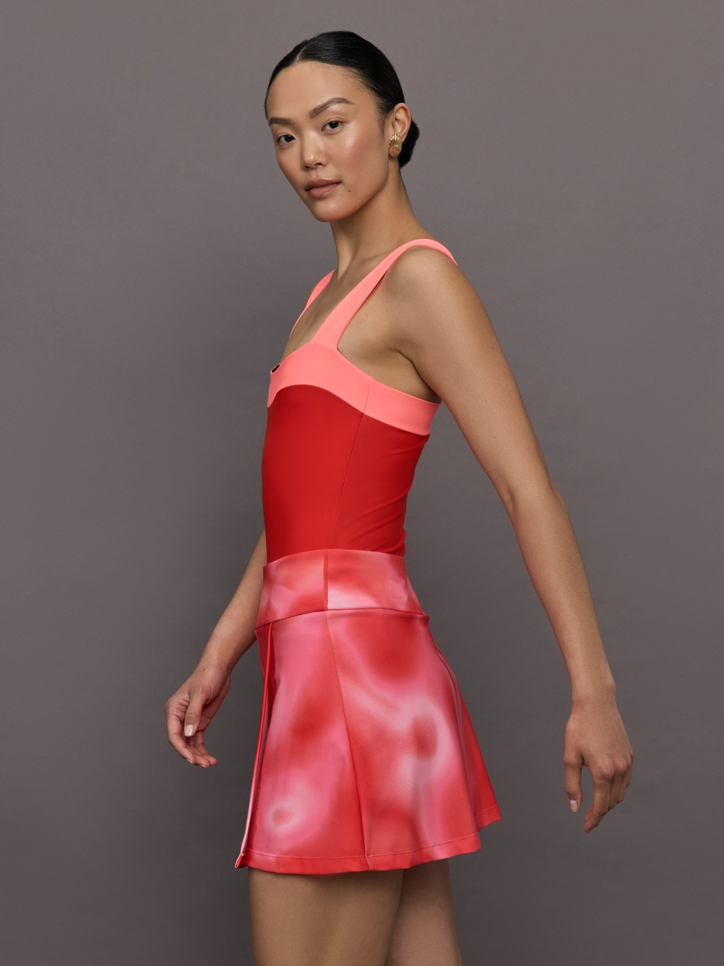 Model wears a high cut one piece square neck bathing suit in red with coral edges. 