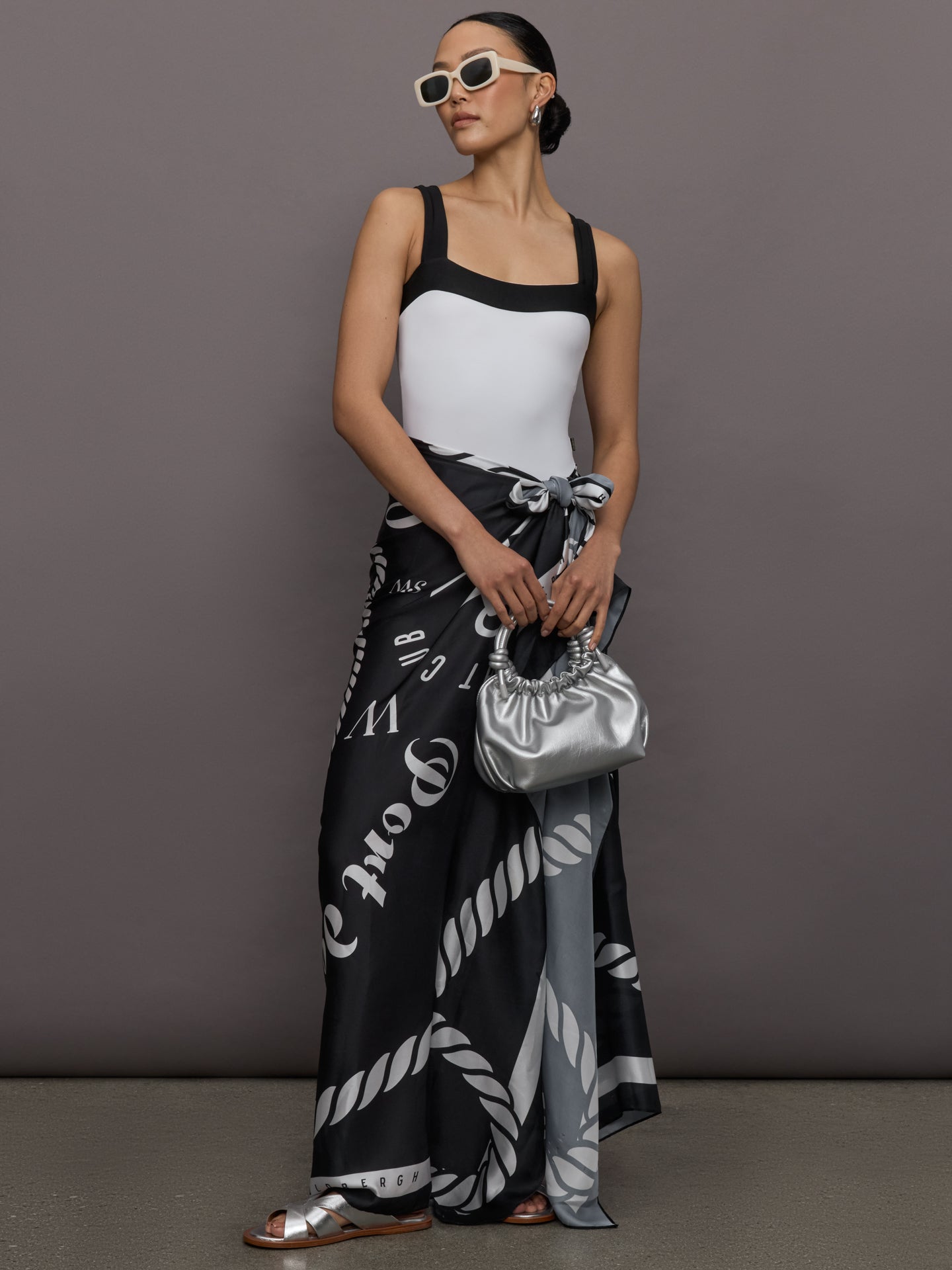 Model wears a high cut one piece square neck bathing suit in white with black edges. 