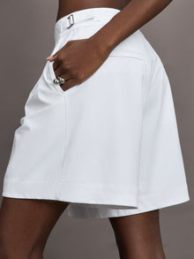Model wears a pair of white pleated culotte wide leg mid rise waisted shorts. 