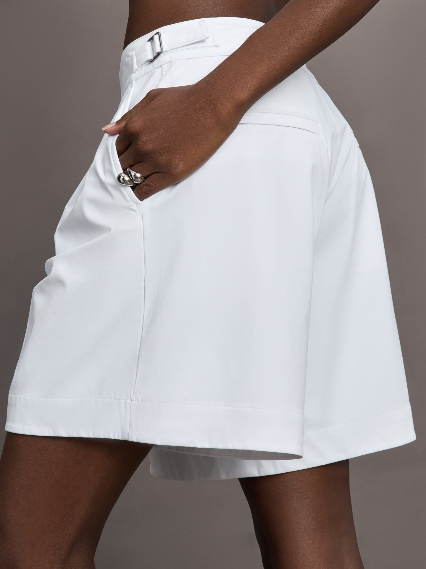 Model wears a pair of white pleated culotte wide leg mid rise waisted shorts. 