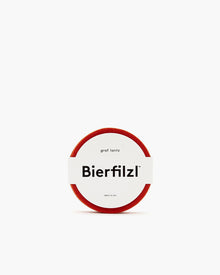 A round red felt coaster made from German Merino wool by graf lantz. It has a clean white label in the center with Bierfilzl in bold, accompanied by smaller text above and below, all set against a stark white background for a minimalist design.