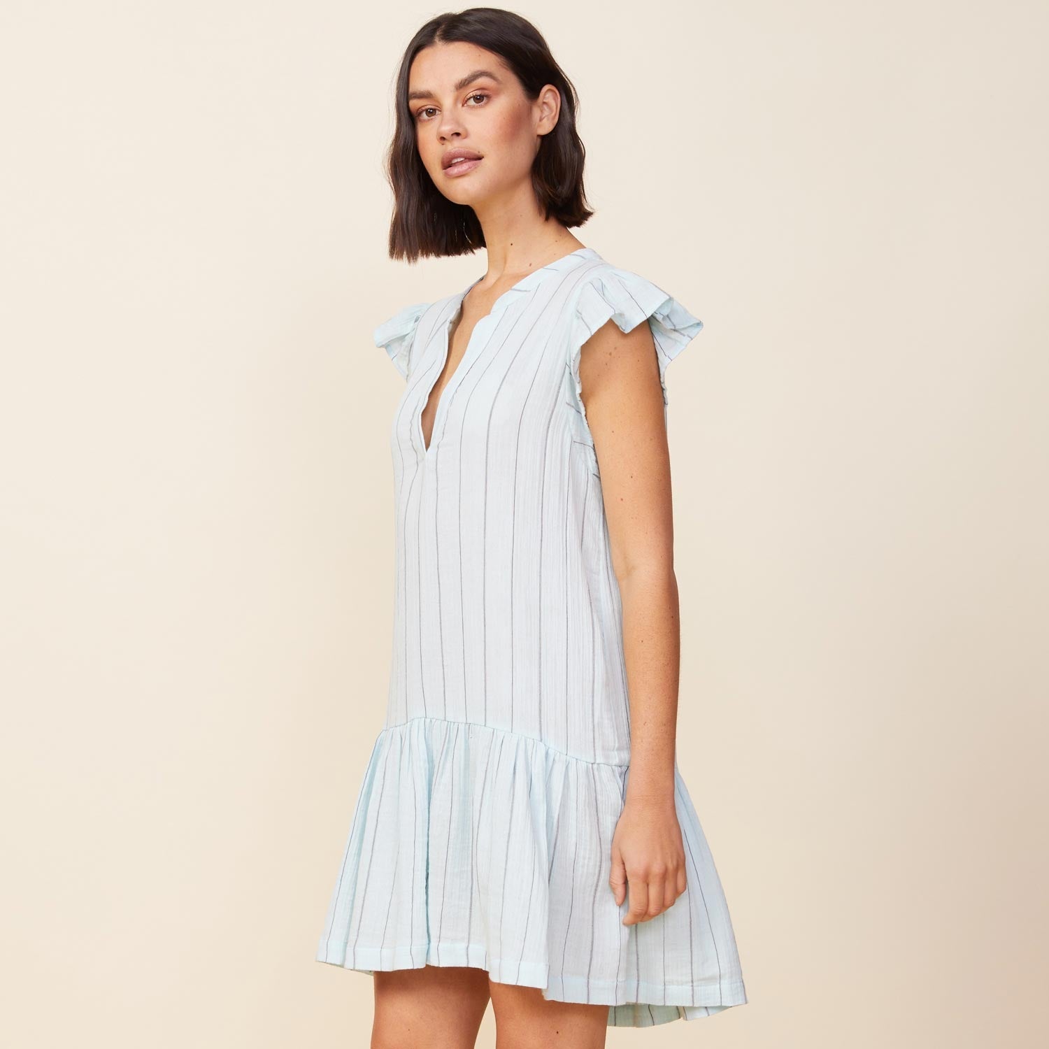 Side view of model wearing the pinstripe gauze easy ruffle dress in sea foam.