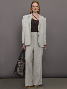Model wears a gray/taupe textured oversized blazer with single button closure.