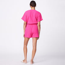 Back view of model wearing the gauze wrap romper in raspberry.